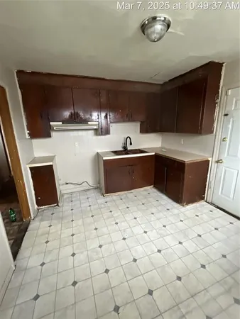 a kitchen with a sink a stove top oven and cabinetry