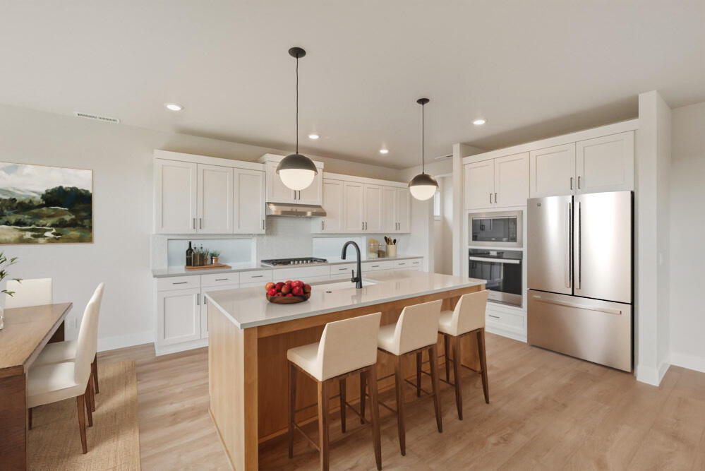 3915 Northeast Oakside Loop Bend, OR 97701 - Photo 4 of 27 a kitchen with stainless steel appliances a dining table chairs refrigerator and microwave