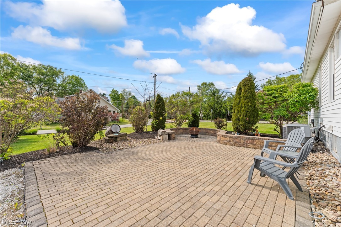 258 Randolph Road Mogadore, OH 44260 - Photo 35 of 49 Paver patio featuring a stone retaining wall with integrated landscaping, mature shrubs, and evergreen trees