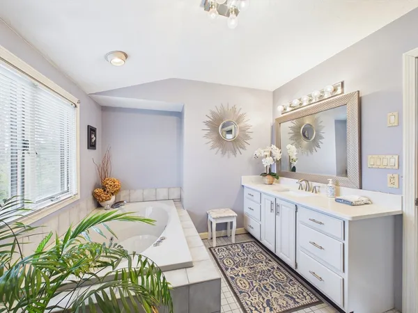 a spacious bathroom with a granite countertop bathtub a sink and a mirror