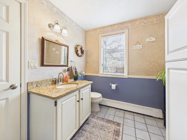a bathroom with a granite countertop sink a toilet a mirror and a window