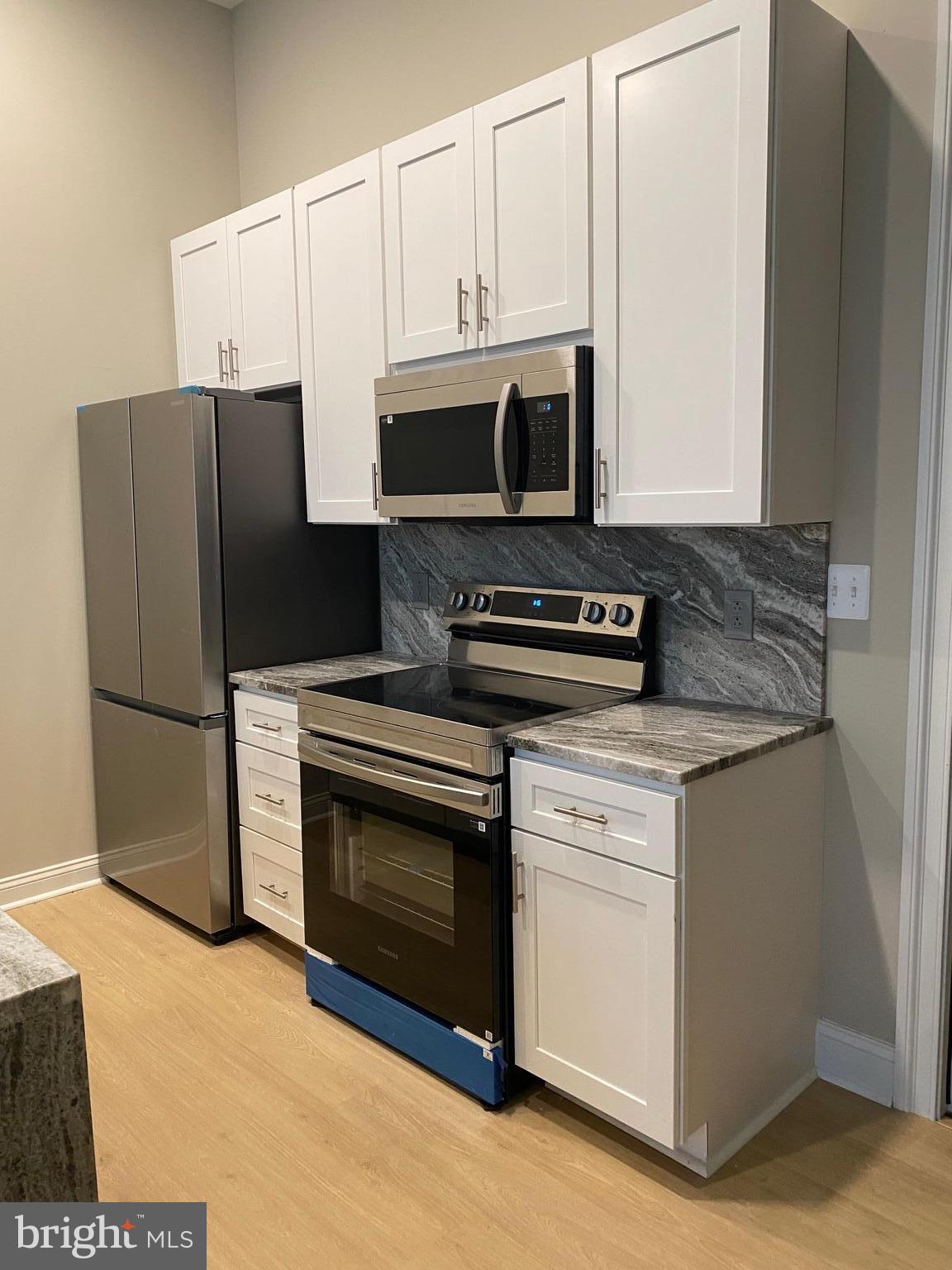 1900-20 Arch Street, Unit 108 Philadelphia, PA 19103 - Photo 2 of 27 a kitchen with stainless steel appliances white cabinets and a stove a refrigerator with wooden floor