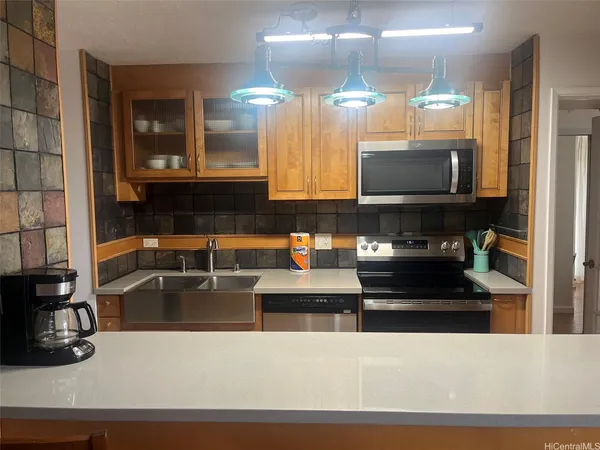 a kitchen with kitchen island granite countertop a sink a stove and a microwave