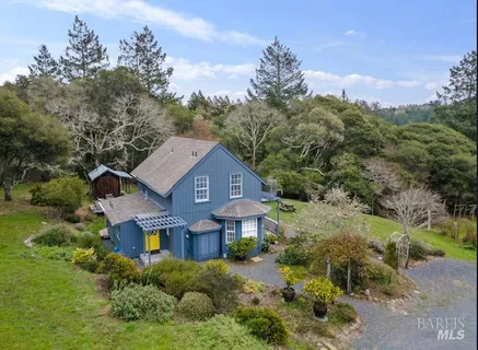 a front view of a house with a yard and large trees