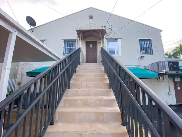 a view of staircase with lots of frames on wall and a view of a house