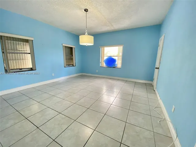 a view of an empty room with window and chandelier fan