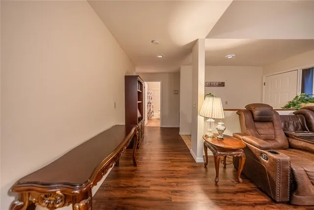 a view of a hallway with wooden floor and a bathroom