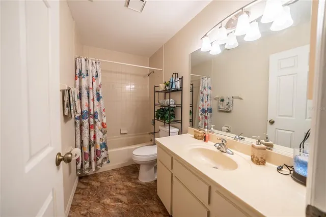 a view of a hallway with wooden floor and a bathroom