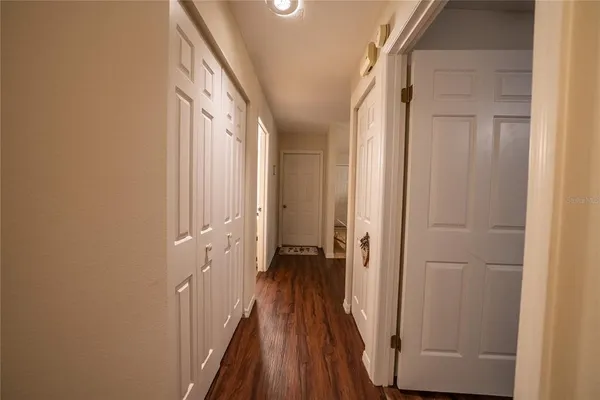 a view of a hallway with wooden floor and a bathroom