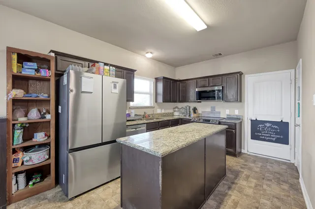 a kitchen with stainless steel appliances granite countertop a refrigerator and a stove top oven