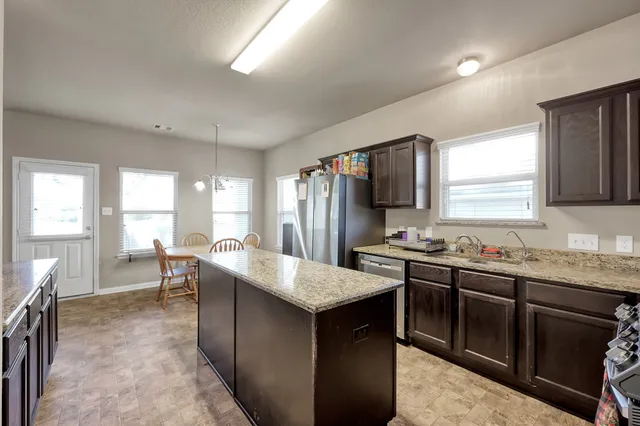 a kitchen with granite countertop a sink stove and refrigerator