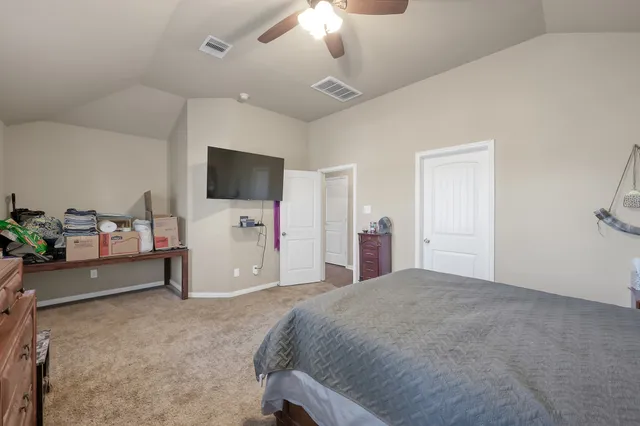 a bedroom with a bed and a flat tv screen on the dresser