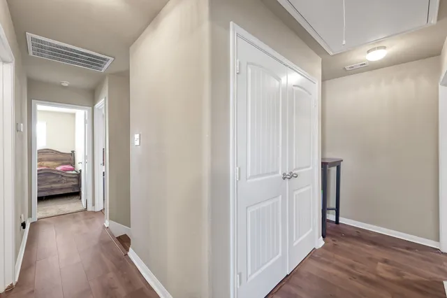 a view of a hallway with wooden floor and closet