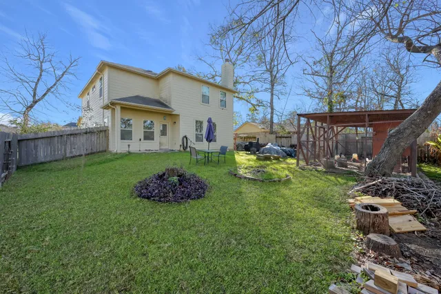 a backyard of a house with wooden table and chairs