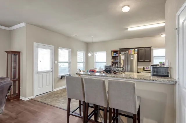 a dining hall with stainless steel appliances granite countertop a dining table and chairs