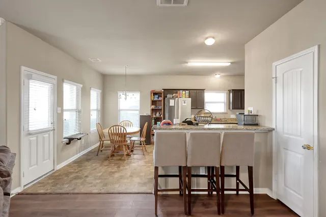 a dining hall with stainless steel appliances granite countertop a table and chairs