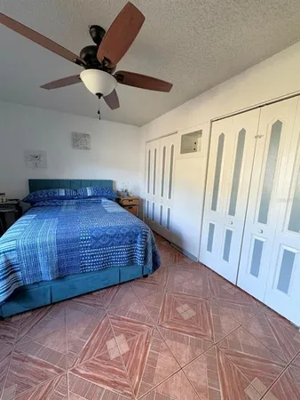 a bedroom with a large bed and a chandelier fan