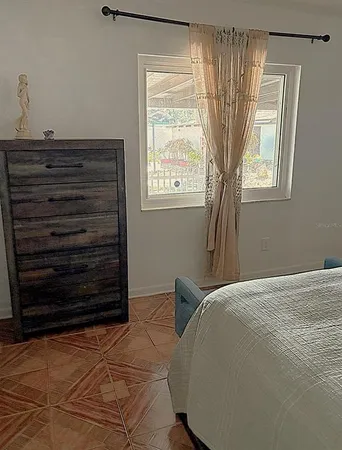 a bed sitting in a bedroom next to a window and dresser