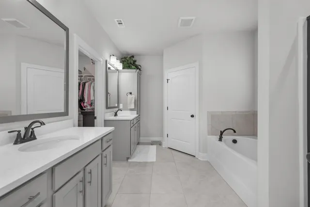 a spacious bathroom with a bathtub sink double and mirror