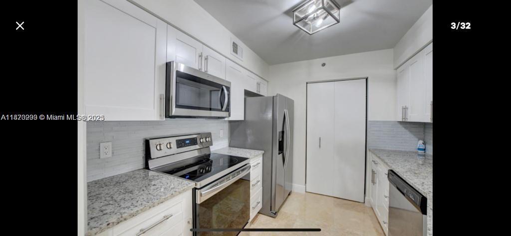 a kitchen with stainless steel appliances granite countertop a refrigerator a stove a sink and a microwave