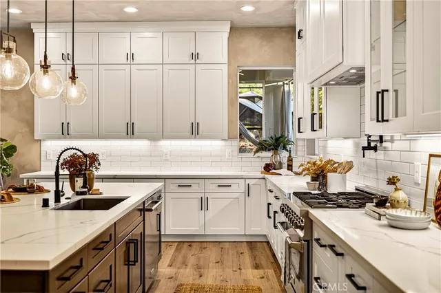 a large kitchen with stainless steel appliances a stove center island wooden floor and living room view