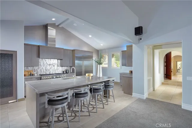 a kitchen with stainless steel appliances granite countertop table chairs stove and refrigerator