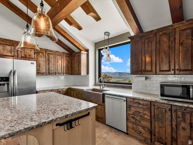 1225 Old Oregon Road Soda Springs, ID 83276 - Photo 11 of 67 Kitchen featuring exposed wood beams, wood cabinetry, stainless steel appliances, granite countertops, and a large window overlooking distant mountains