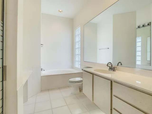 a bathroom with a granite countertop sink a toilet and a mirror