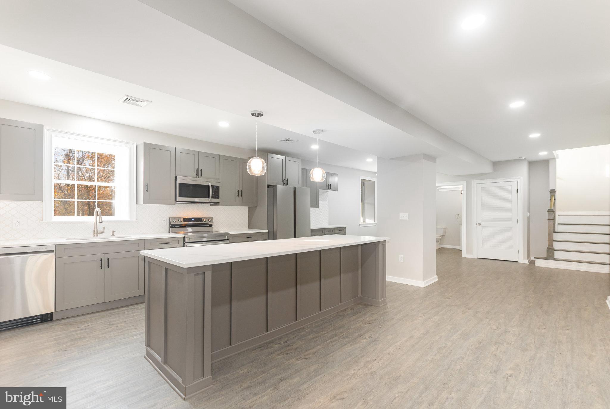 481 Sample Bridge Road Enola, PA 17025 - Photo 11 of 55 a large kitchen with kitchen island a sink a stove a refrigerator and a dining table with wooden floor