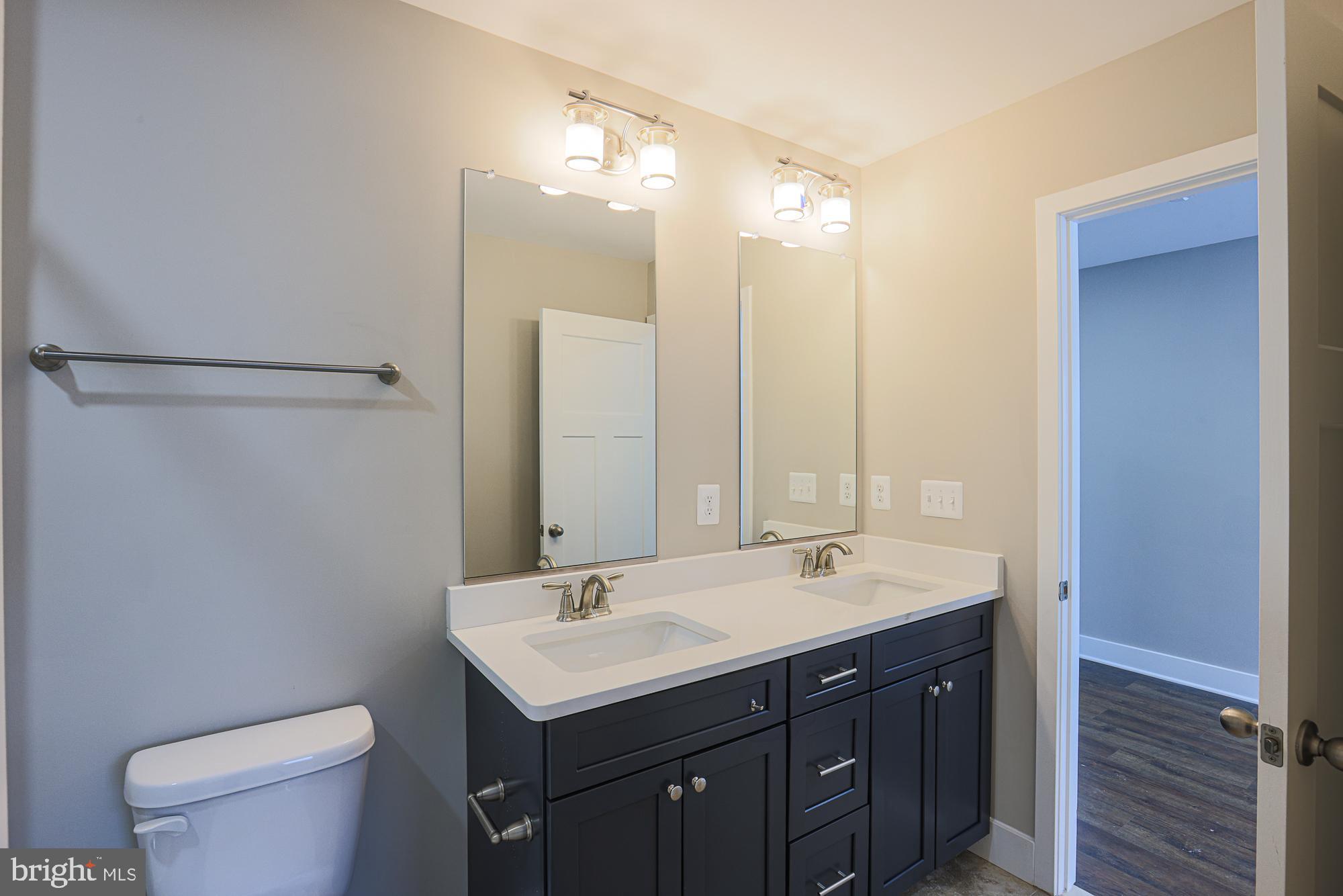 4712 Carroll Manor Road Baldwin, MD 21013 - Photo 40 of 69 a bathroom with a double vanity sink toilet and a mirror