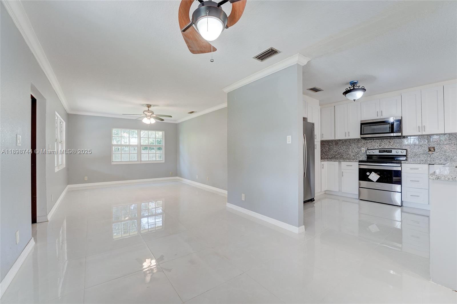 5130 Southwest 208th Lane Southwest Ranches, FL 33332 - Photo 14 of 53 a kitchen with kitchen island white cabinets stainless steel appliances and window