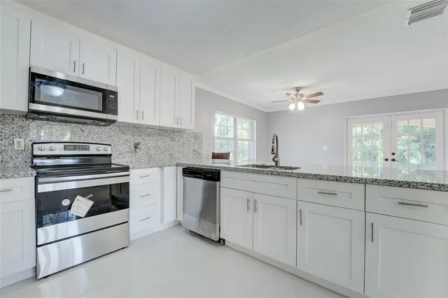 a kitchen with white cabinets and appliances