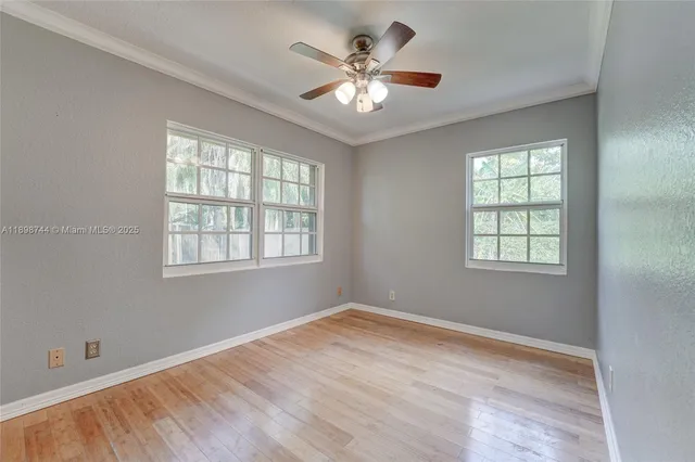 a view of an empty room with a window and wooden floor
