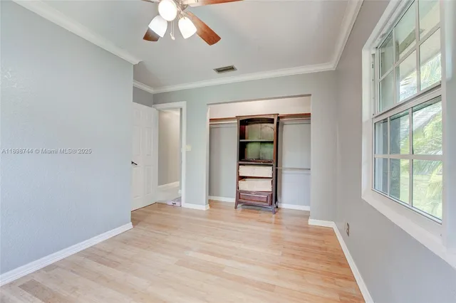 a view of empty room with wooden floor and fan