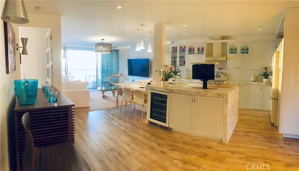 a living room with stainless steel appliances furniture a rug kitchen view and a chandelier