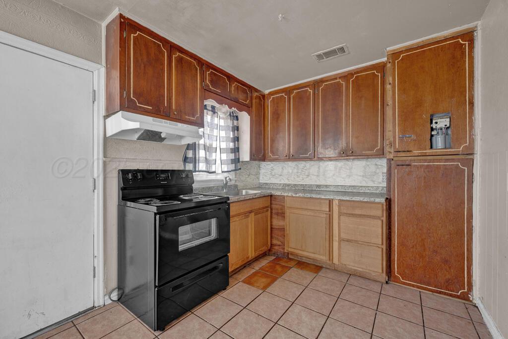 108 Spruce Avenue Dumas, TX 79029 - Photo 7 of 15 a kitchen with stainless steel appliances granite countertop a stove a sink and a refrigerator
