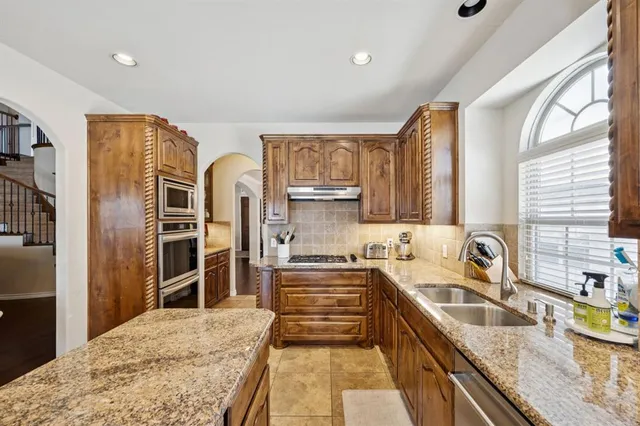 a kitchen with stainless steel appliances granite countertop a sink stove and refrigerator