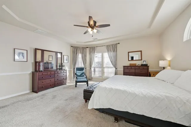 a bedroom with a large bed and a chandelier fan