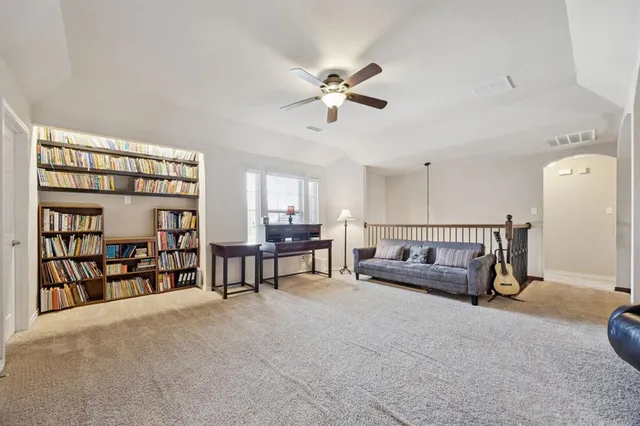 a living room with furniture a ceiling fan and a book shelf