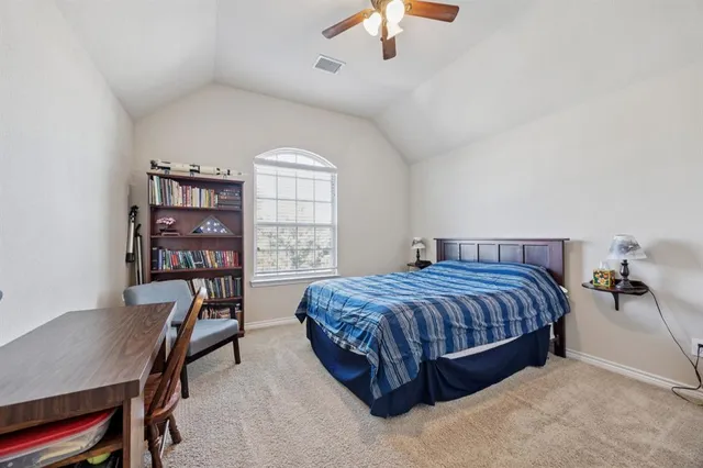 a spacious bedroom with a bed a table and a bookshelf