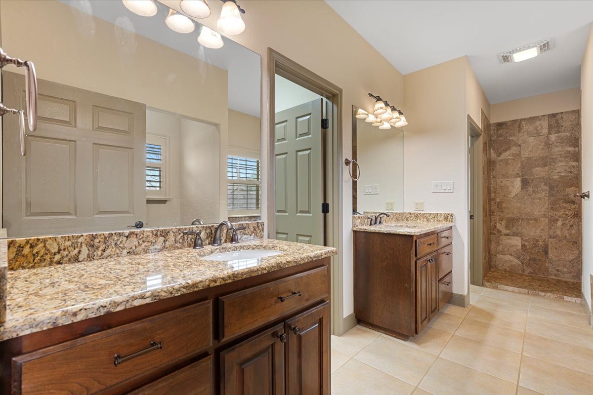 106 Spring Meadow Road Bastrop, TX 78602 - Photo 19 of 39 Full bath with two vanities, light tile patterned floors, and a walk in shower