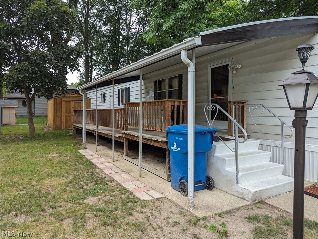 35157 Center Ridge Road, Unit 112 North Ridgeville, OH 44039 - Photo 2 of 9 Rear view of house featuring a wooden deck, a lawn, and a storage shed