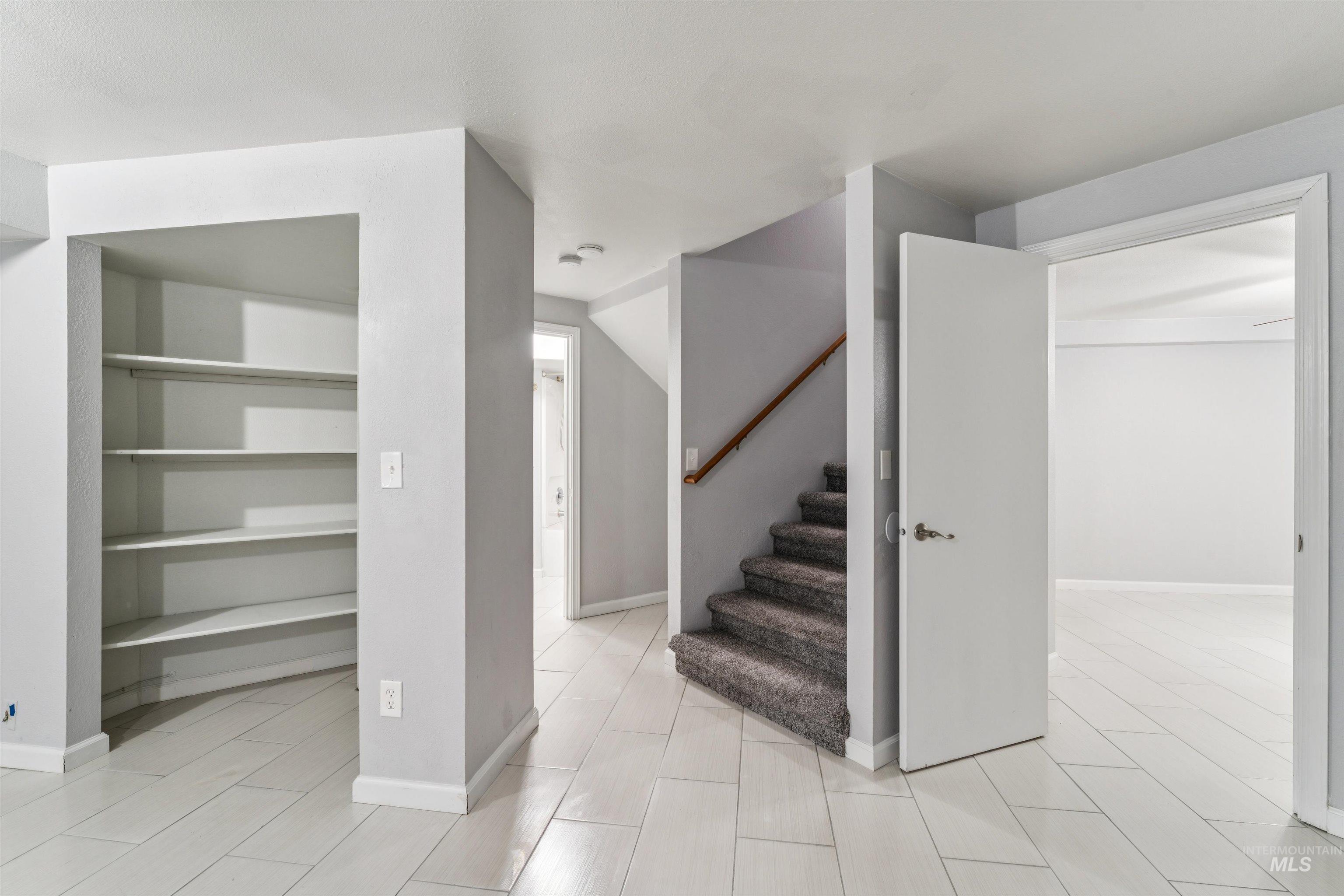 9831 West Ripley Street Boise, ID 83704 - Photo 30 of 47 Interior hallway featuring light wood-finish flooring, a carpeted staircase with wood handrail, an open doorway, and a built-in shelving unit