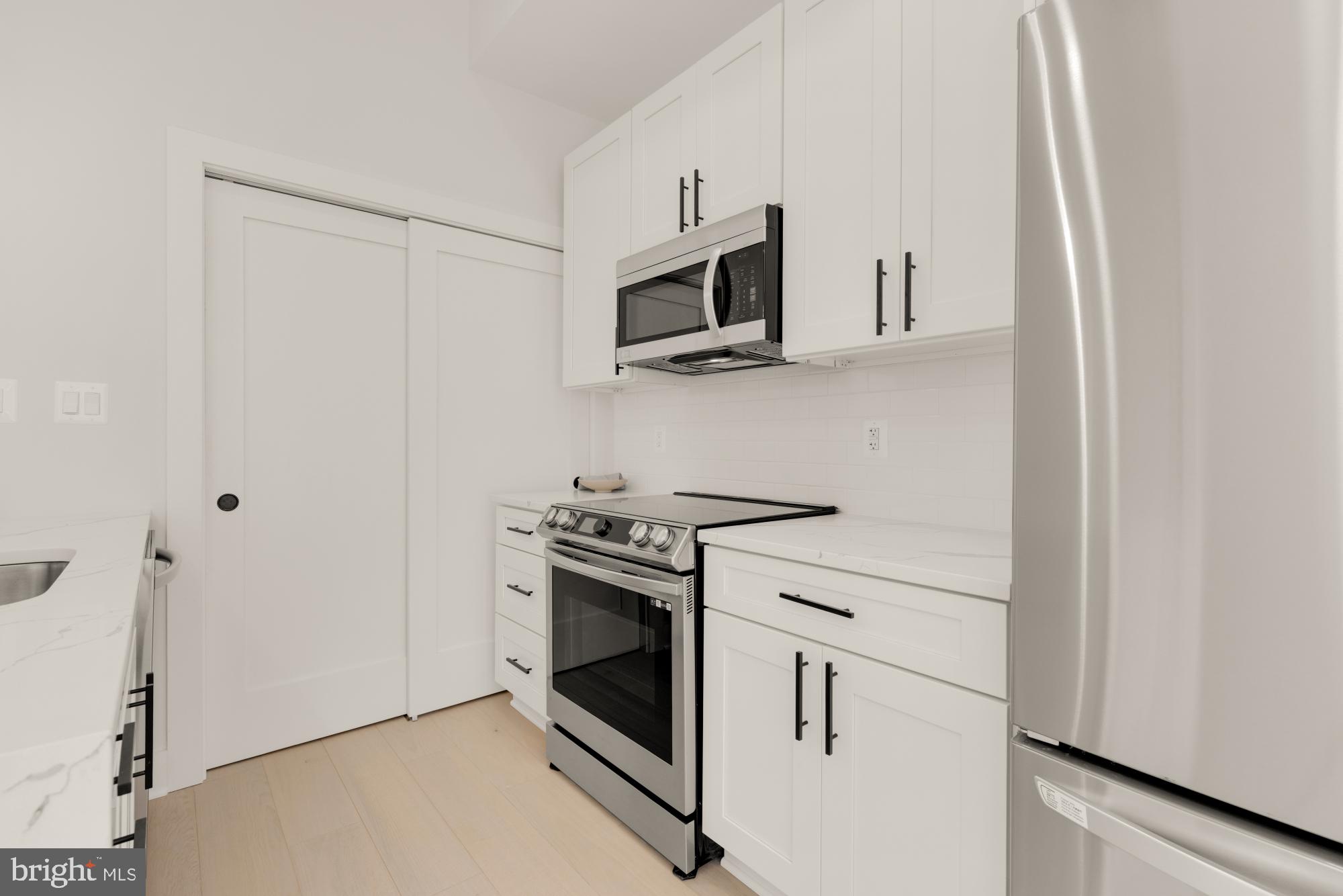 5505 7th Street Northwest, Unit 5 Washington, DC 20011 - Photo 7 of 27 a kitchen with stainless steel appliances white cabinets and a stove