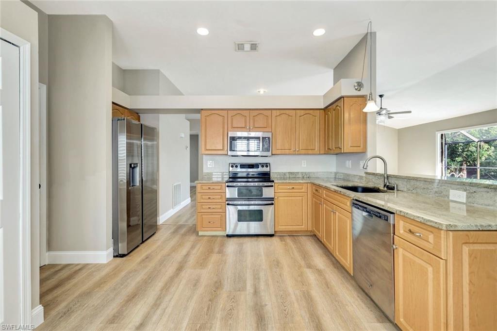 3650 Kent Drive Naples, FL 34112 - Photo 13 of 40 a kitchen with stainless steel appliances granite countertop a sink and wooden cabinets