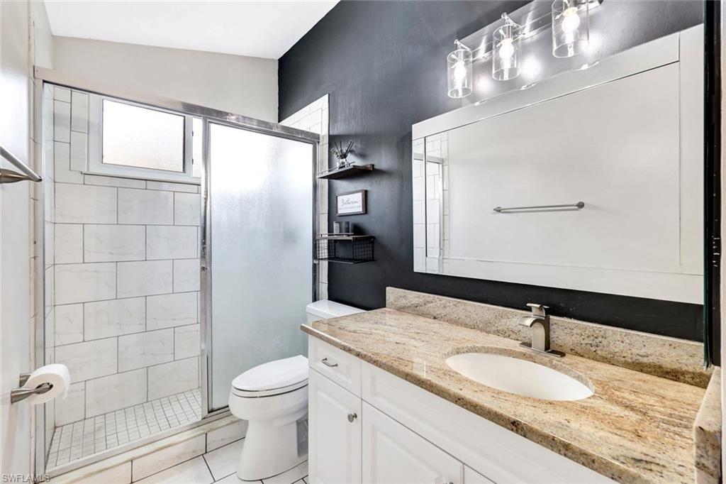 3650 Kent Drive Naples, FL 34112 - Photo 20 of 40 a bathroom with a granite countertop sink a toilet and a mirror