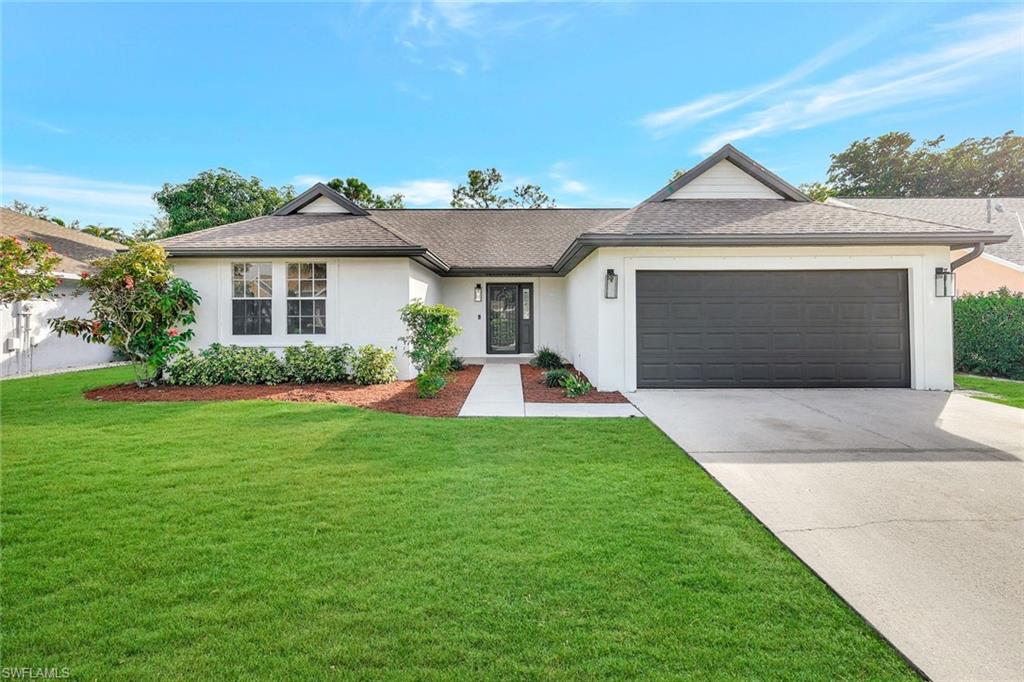 3650 Kent Drive Naples, FL 34112 - Photo 2 of 40 a front view of a house with a yard and garage