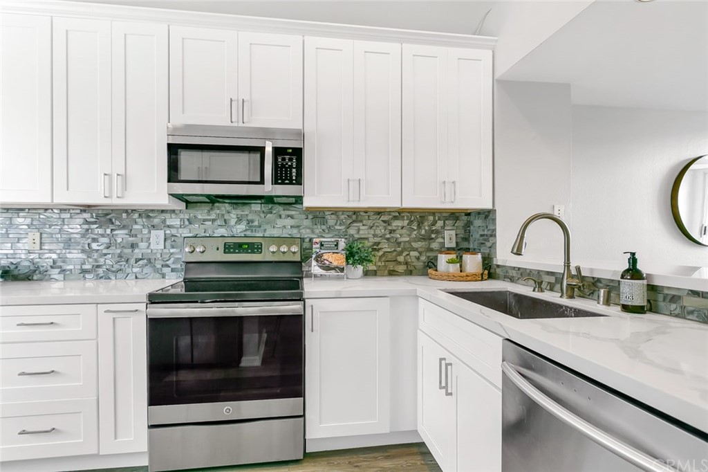 20331 Bluffside Circle, Unit A416 Huntington Beach, CA 92646 - Photo 5 of 42 a kitchen with white cabinets and stainless steel appliances