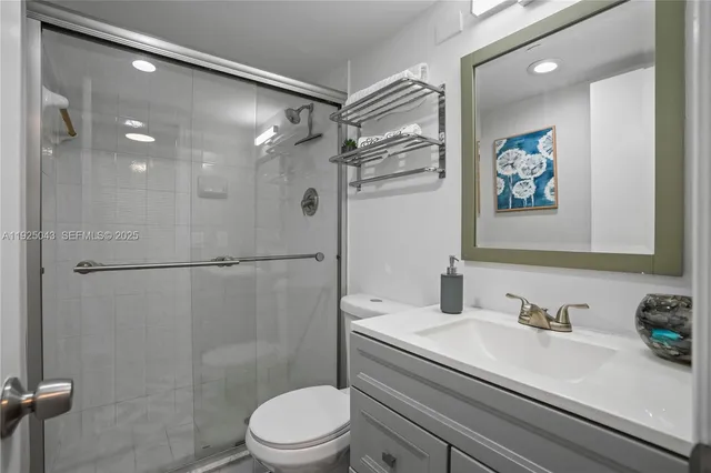 a bathroom with a granite countertop sink a toilet a shower and a mirror