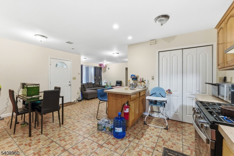 29 22nd Avenue Paterson, NJ 07513 - Photo 4 of 20 a kitchen with stainless steel appliances granite countertop a stove top oven a dining table and chairs with wooden floor